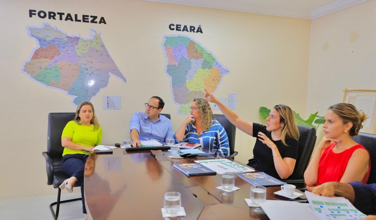 Gabriella Aguiar e Jade Romero, acompanhadas de assessores, numa sala de reunião